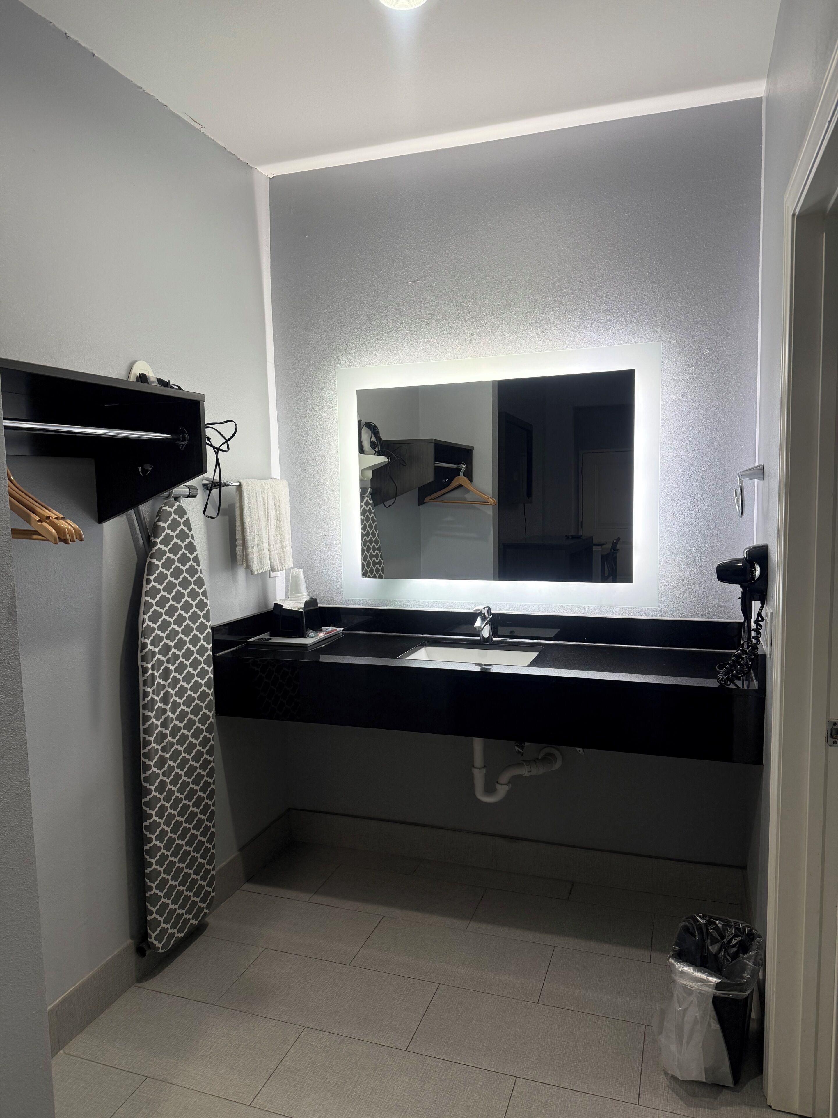 Une salle de bain moderne avec un plan de toilette noir, un miroir et un porte-serviettes.