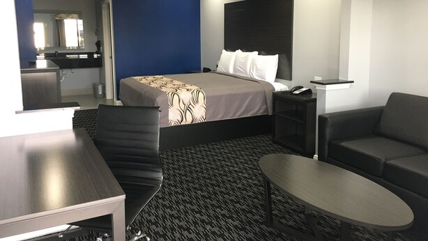 Une chambre d’hôtel moderne équipée d’un lit, d’un bureau, d’une chaise, d’un canapé et d’une petite table.