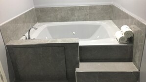 Une salle de bain moderne avec une baignoire sur pieds, des carreaux de marbre et un espace douche intégré.