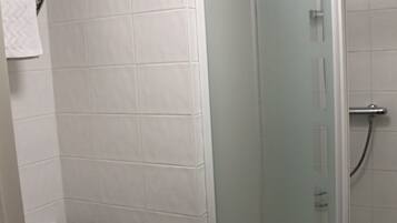 Un baño con inodoro, cabina de ducha de vidrio y perchero para toallas.