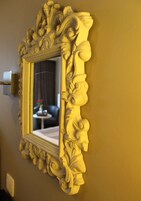 A mirror with an ornate gold frame mounted on a wall.