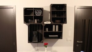 Um banheiro moderno com duas cadeiras brancas, uma mesa redonda e prateleiras com produtos de higiene pessoal.