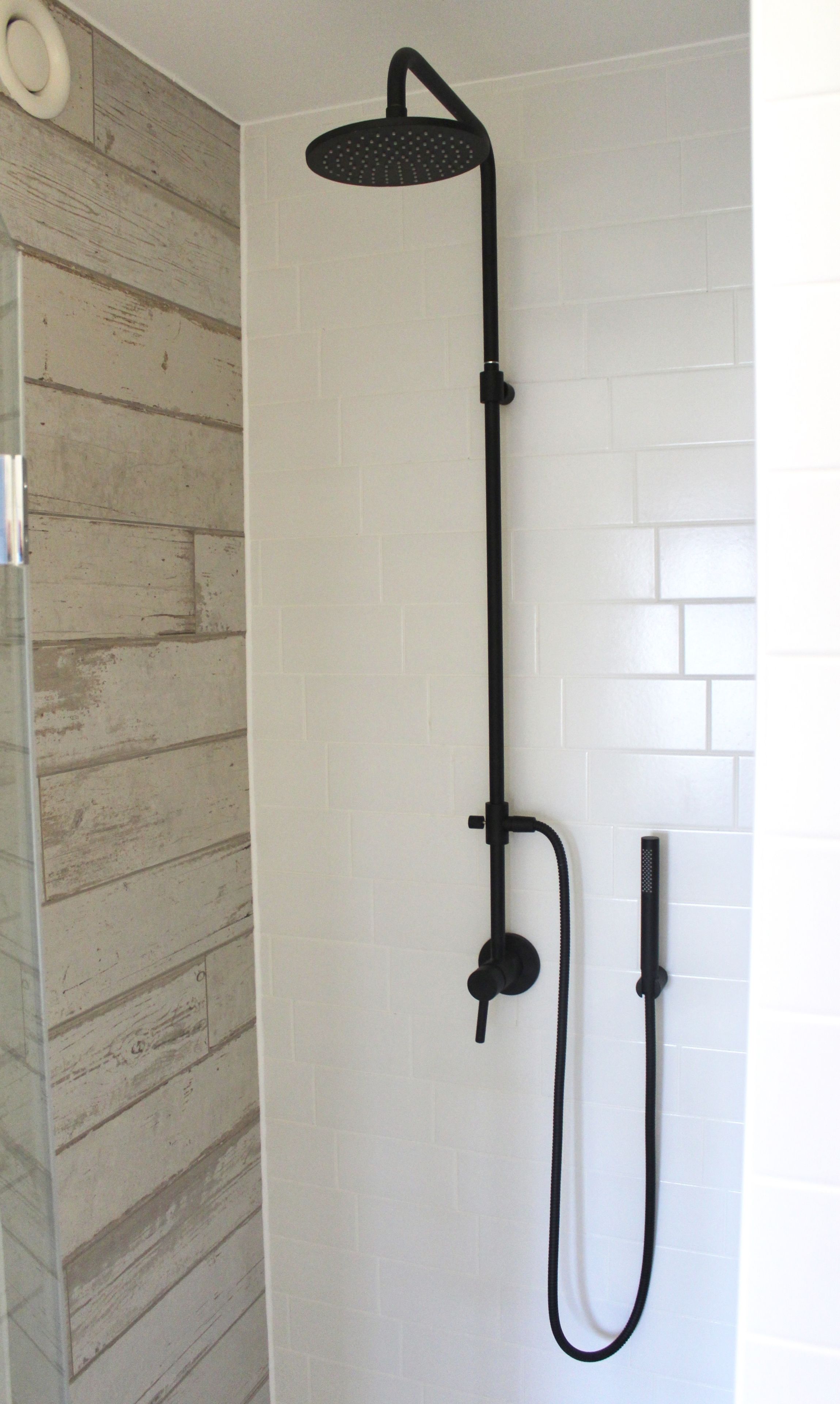 Une douche équipée d’un pommeau de douche à main et d’un flexible à main.