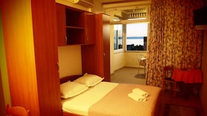 A hotel room with a bed, a small table, a chair, and a view of the outdoors. - Apartments Dany (Makarska)