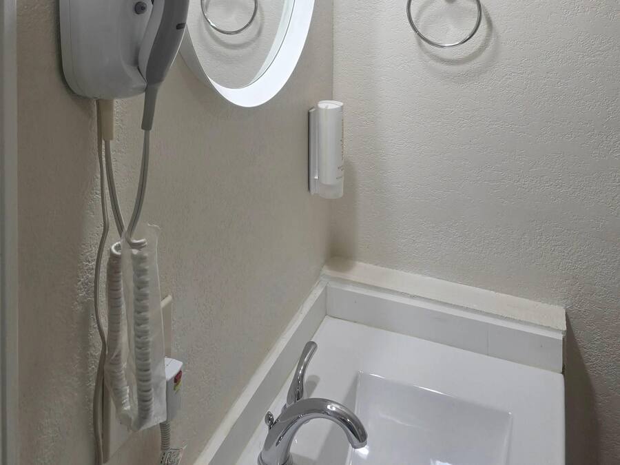 Un baño con una bañera blanca, un dispensador de toallas en la pared y un teléfono.