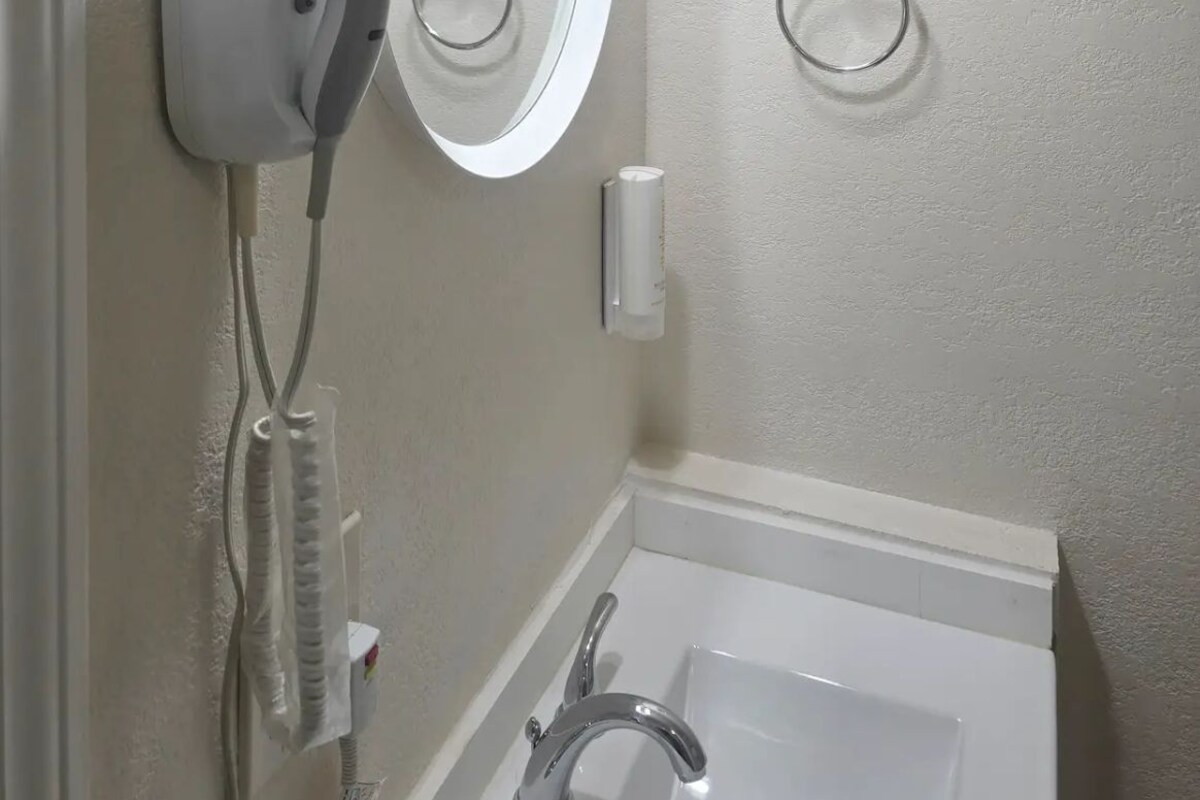 A bathroom with a bathtub, a handheld showerhead, and a towel rack.