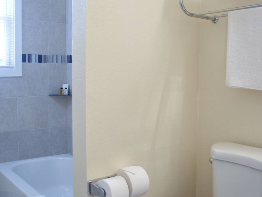 A bathroom with a bathtub, toilet, and a towel rack.