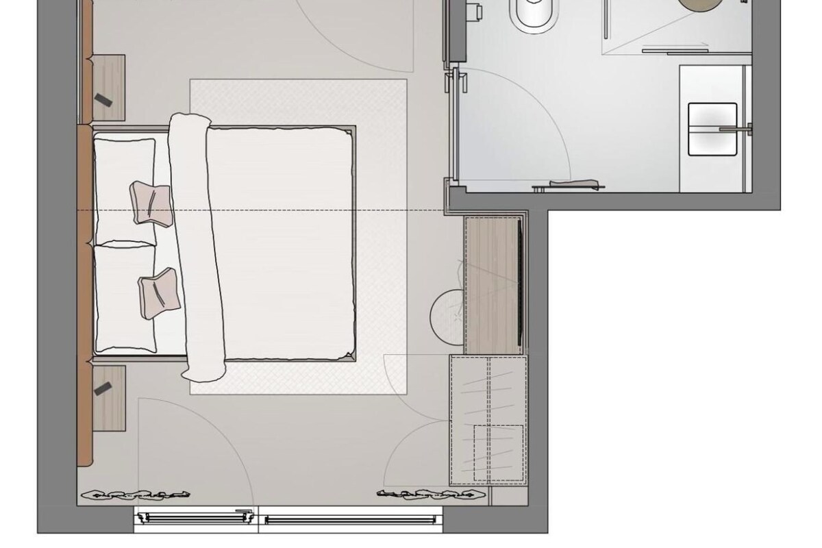 A hotel room layout with a bed, bedside tables, a bathroom with a toilet and sink, and a small sitting area.