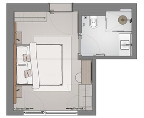 A hotel room layout with a bed, bedside tables, a bathroom with a toilet and sink, and a small sitting area.