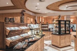 A wooden interior with a breakfast buffet, wooden cabinets, and a central island with food displays.