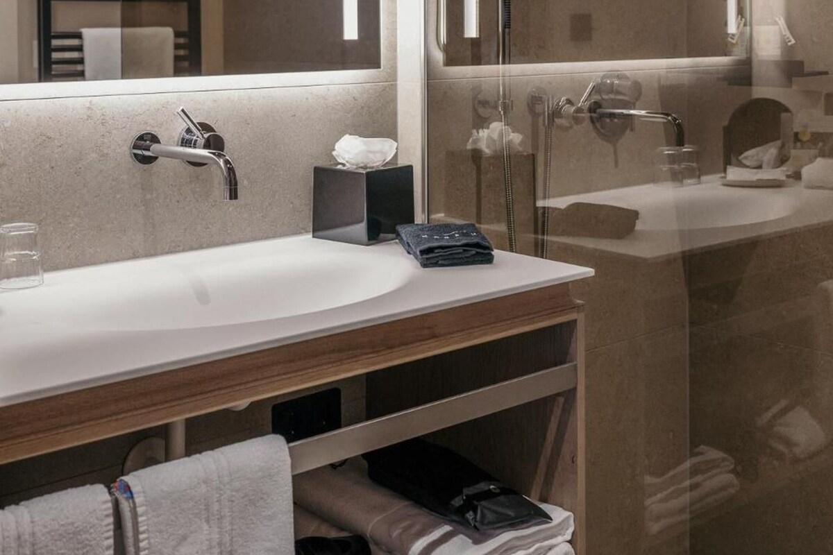 A modern bathroom with a large mirror, a shower, and a vanity with a towel rack.