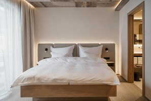 A modern bedroom with a wooden bed frame, two bedside tables, and a headboard with integrated lighting.