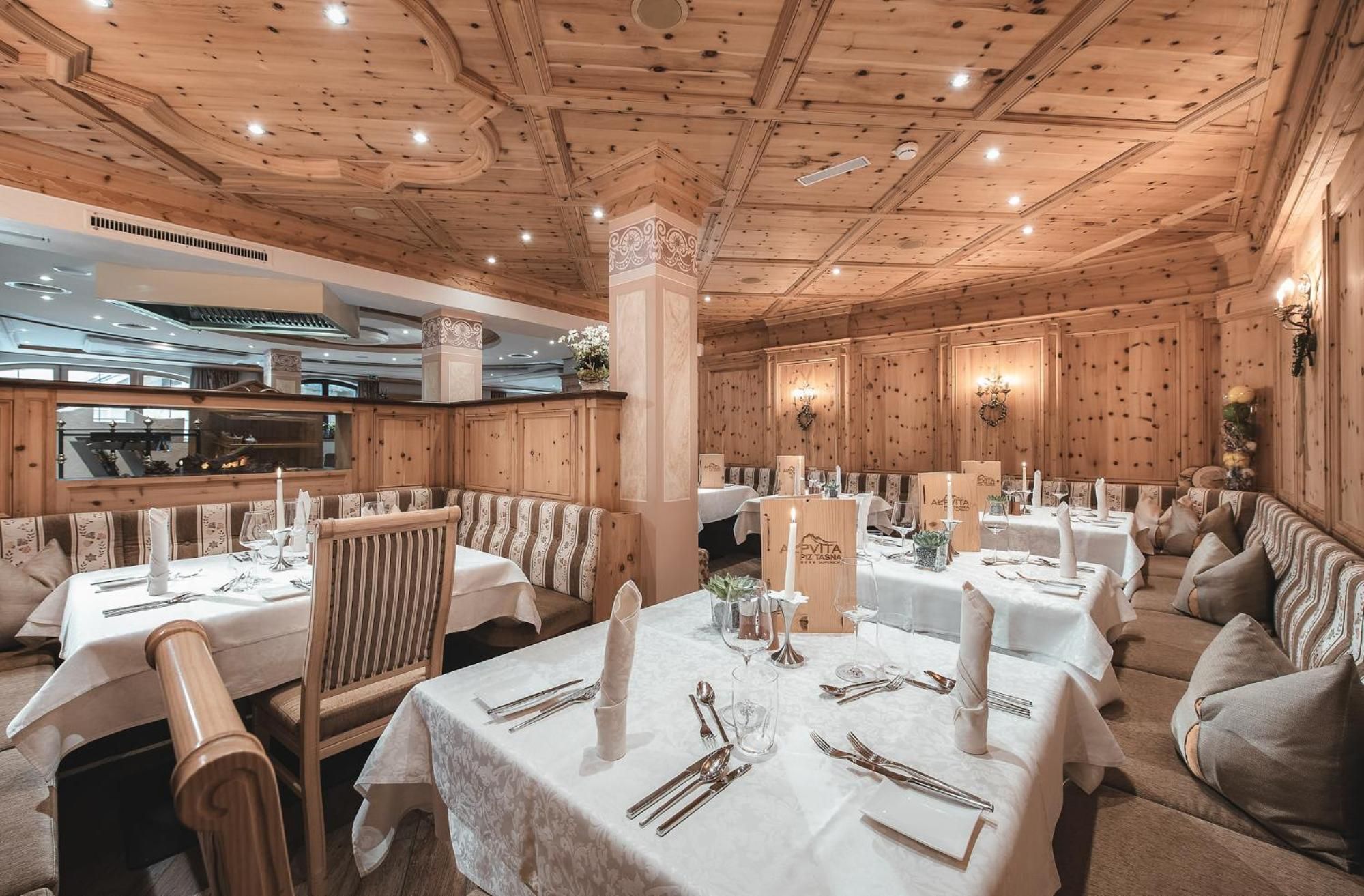 Un restaurante con paneles de madera, manteles blancos y centros de mesa con velas.