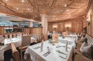 A restaurant with wooden paneling, white tablecloths, and candle centerpieces.