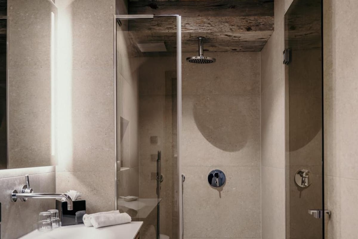 Un baño moderno con ducha envuelta en vidrio, tocador de madera con lavamanos y un perchero para toallas.