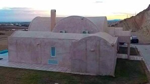 Una casa moderna con un diseño arquitectónico único, que presenta una gran cúpula central y una estructura más pequeña adosada.