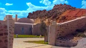 Un edificio con un patio, una gran estructura abovedada y un cerro rocoso al fondo.