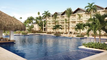 Relax by the resort pool surrounded by palm trees and lounge chairs.