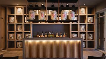 A bar area with a wooden counter, shelves with jars, and bottles.