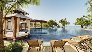 A poolside area with lounge chairs, a cabana, and palm trees. - Secrets La Romana Resort & Spa  - Adults Only - All Inclusive (San Rafael del Yuma)