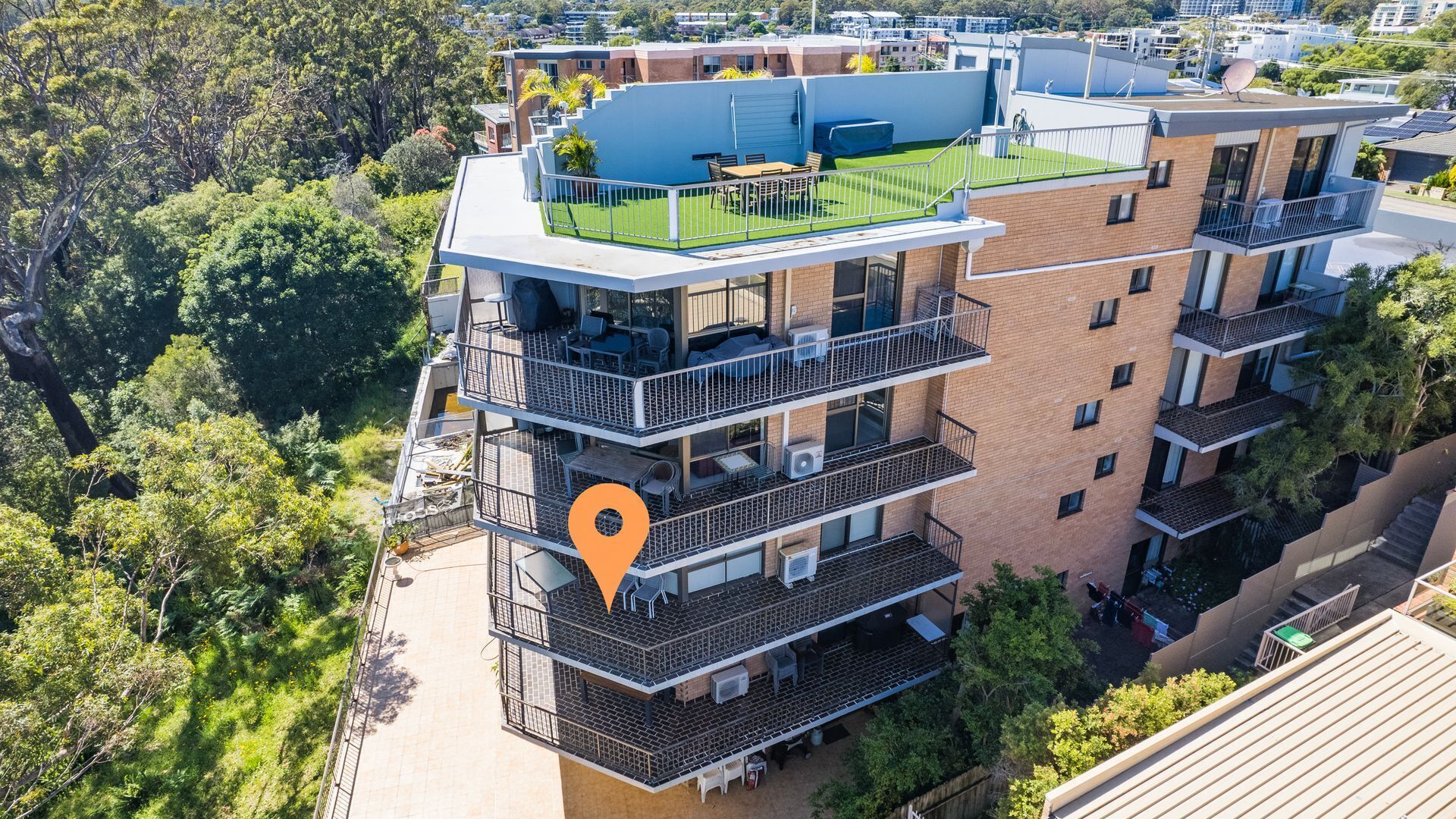 A multi-story building with balconies, a rooftop garden, and a location marker.