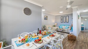 Un coin repas avec une table mise pour le repas, une horloge au mur et un ventilateur de plafond.