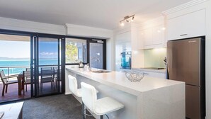 A modern kitchen with a large island, stainless steel appliances, and a view of the ocean. - Florentine, 12/11 Columbia Close - WIFI, Aircon, spectacular views (Nelson Bay)