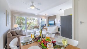 A modern kitchen with a dining area, a sofa, and a TV. - Sebastapol, 4,66 Thurlow Avenue - Unit with wonderful views across the bay (Nelson Bay)