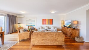 Una sala de estar con muebles de mimbre, un televisor y obras de arte en la pared.