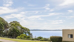 Udsigt over kysten med klart himmel, et vandområde og fjerne bjerge i horisonten.