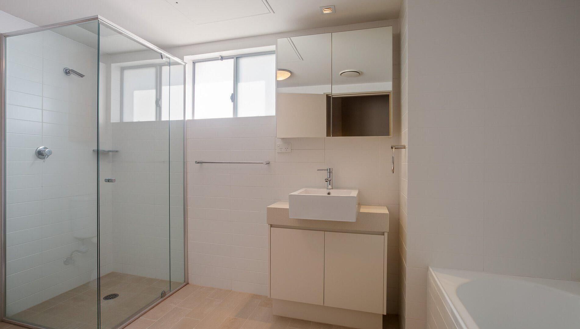 Un bagno moderno con cabina doccia in vetro, un lavandino bianco e un mobile contenitore.