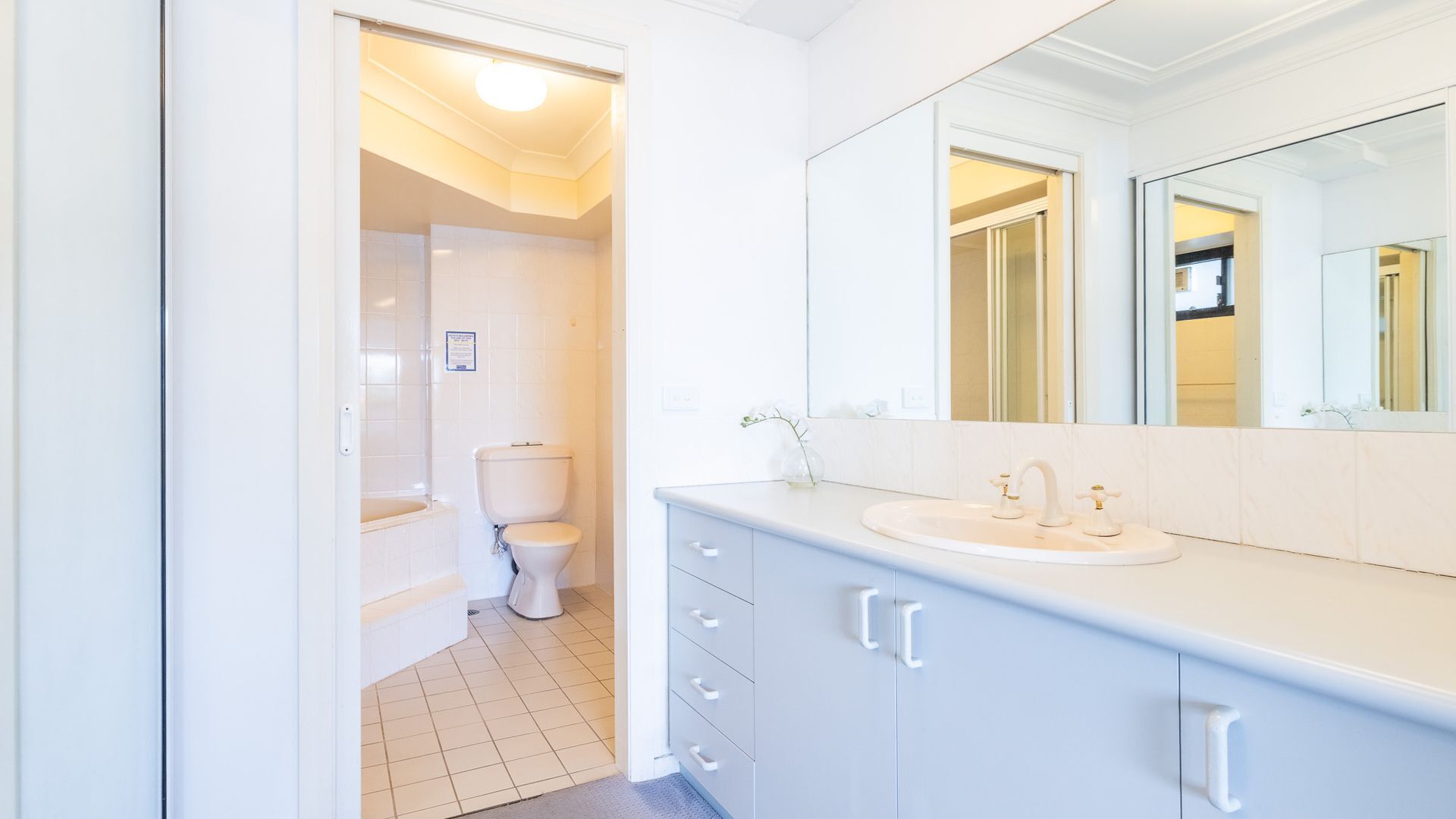 A modern bathroom with a white sink, vanity, and toilet.