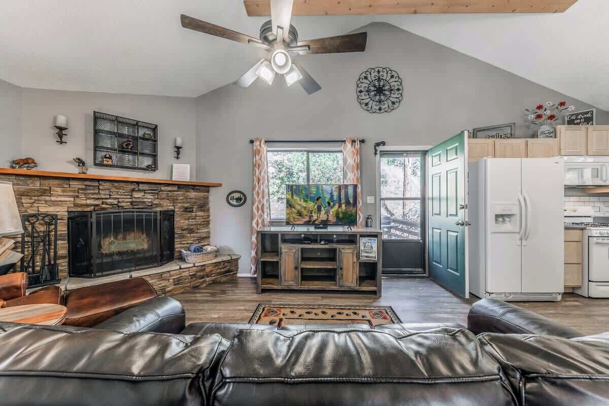 A living room with a fireplace, leather sofa, and a television.