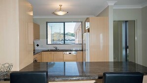 Una cocina moderna con encimera de granito, armarios de madera y una ventana con persianas.