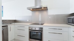 A modern kitchen with white cabinetry, stainless steel appliances, a built-in oven, and a microwave. - Collendina, 4/19 Kurrawa Close - fantastic water views and sea breezes (Nelson Bay)