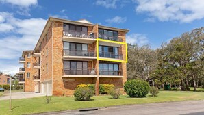 A multi-story brick building with balconies, a garage, and a well-maintained lawn. - Collendina, 4/19 Kurrawa Close - fantastic water views and sea breezes (Nelson Bay)