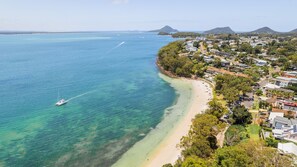 Eine Küstenstadt mit Strand, klarem Wasser und einer Yacht.