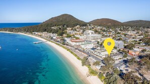 A coastal town with a beach, residential buildings, and a yellow location marker. - Fleetwood, 2/63 Shoal Bay Road - spectacular views (Shoal Bay)