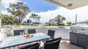 An outdoor patio with a table set for dining, a grill, and a view of the sea and mountains. - Fleetwood, 2/63 Shoal Bay Road - spectacular views (Shoal Bay)