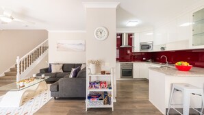 A modern apartment with a living room, kitchen, and staircase. - Bushmans, 9 24 Tomaree Street - Spacious townhouse (Nelson Bay)