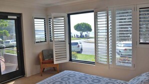 A bedroom with a large window, a chair, and a patterned bedspread. - Florentine, 4/11 Columbia Close - spectacular views and air conditioning (Nelson Bay)