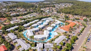 Luchtbeeld van een resort met meerdere gebouwen, een centraal zwembad en een wasserij.