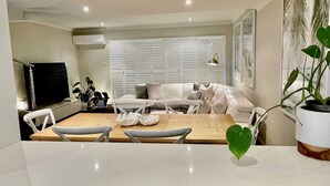 Een moderne woonkamer met een bank, stoelen, een eettafel en een televisie.