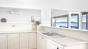 A modern kitchen with a large window overlooking a body of water. - Beached Inn, 93 Foreshore Drive - Spacious beach front house (Salamander Bay)