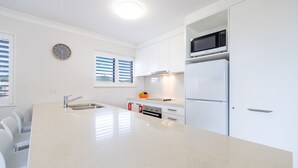 A modern kitchen with white cabinetry, a stainless steel sink, a microwave, and a refrigerator. - Intrepid, 6/3 Intrepid Close - right on the waterfront (Nelson Bay)