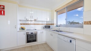 A modern kitchen with white cabinets, a Bosch dishwasher, a microwave, and a stainless steel sink. - Luskin Lodge, 11/29 Weatherly Close - stunning water views (Nelson Bay)