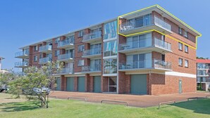 A multi-story residential building with balconies, brick facade, and a clear sky. - Luskin Lodge, 11/29 Weatherly Close - stunning water views (Nelson Bay)