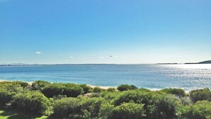 A coastal landscape with a beach and dense greenery in the foreground. - Luskin Lodge, 11/29 Weatherly Close - stunning water views (Nelson Bay)