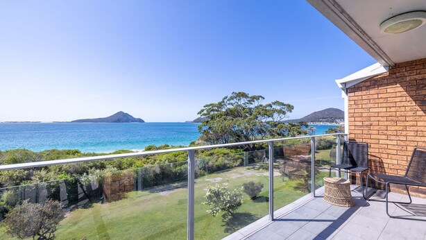 A balcony with a view of the sea, a brick wall, and outdoor furniture. - Luskin Lodge, 11/29 Weatherly Close - stunning water views (Nelson Bay)