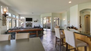 A spacious kitchen with a dining area, a bar, and a television. - Country Club Home w/ Pool & Spa, 2 Mi to Coachella (Indio)